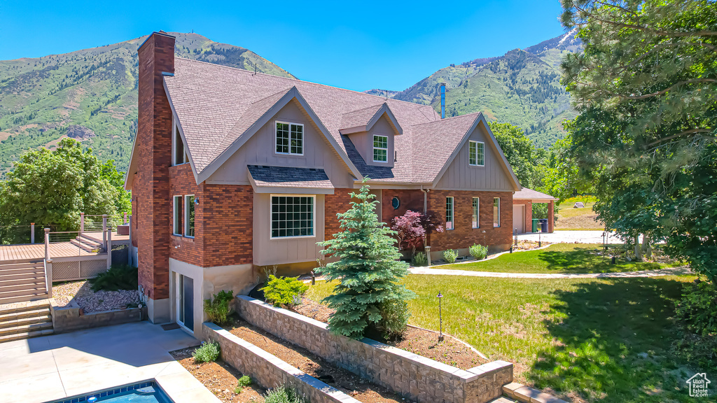 View of front facade with a patio, a mountain view, and a front lawn