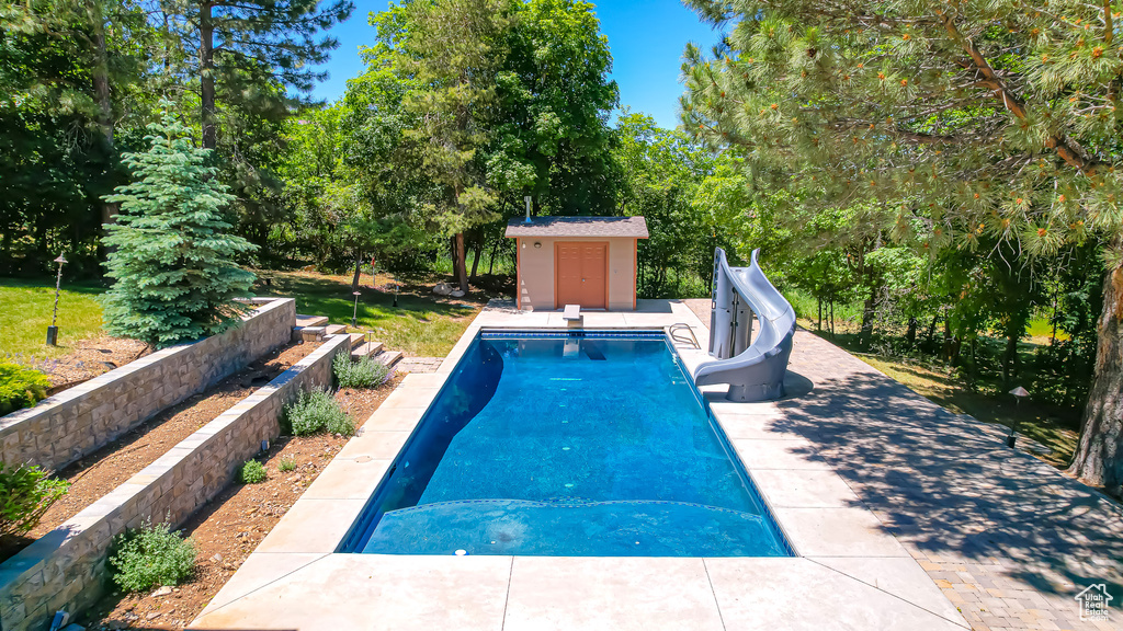 View of swimming pool featuring a patio, an outbuilding, and a water slide