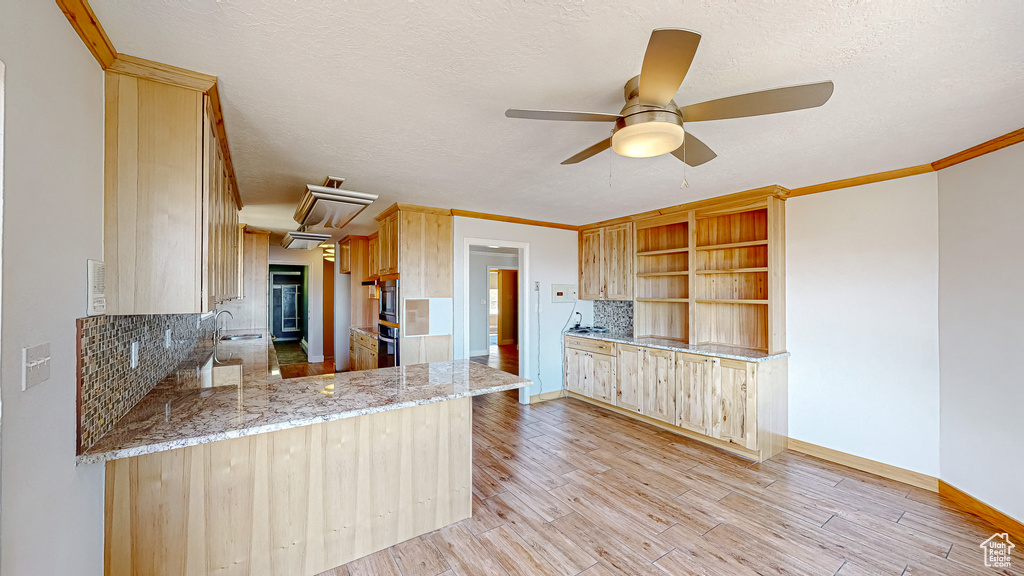 Kitchen with kitchen peninsula, light hardwood / wood-style flooring, backsplash, ceiling fan, and light brown cabinetry