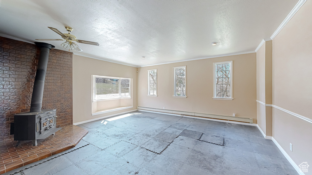 Interior space with ceiling fan, a wood stove, and a healthy amount of sunlight