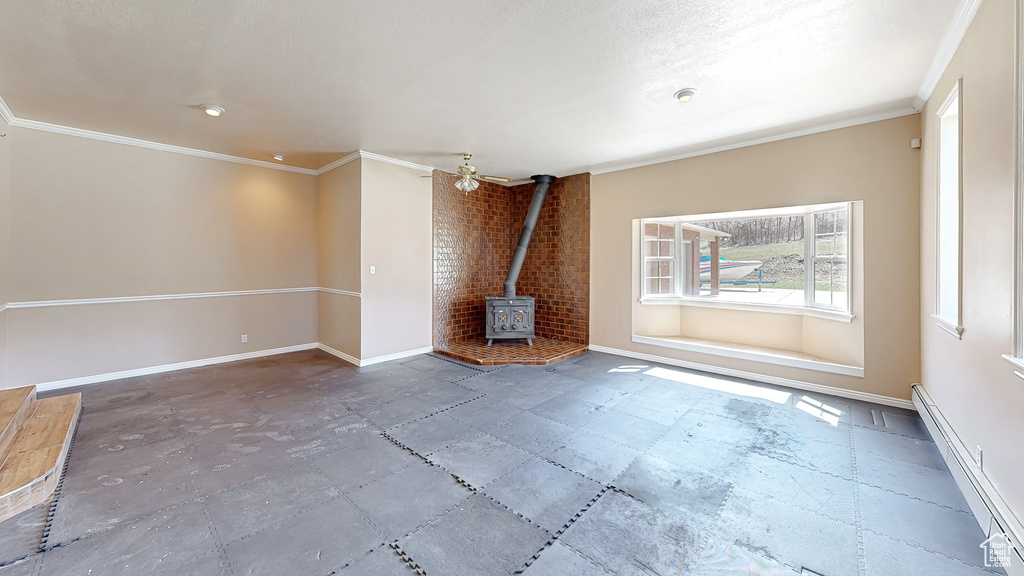 Unfurnished living room featuring a baseboard heating unit, crown molding, and a wood stove