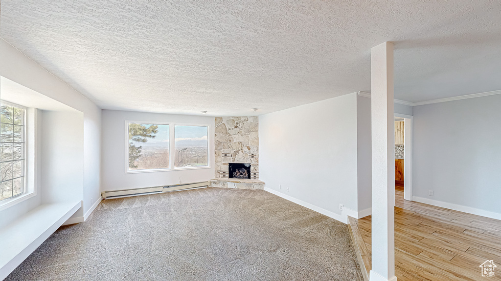 Unfurnished living room featuring a textured ceiling, light hardwood / wood-style flooring, a fireplace, and baseboard heating