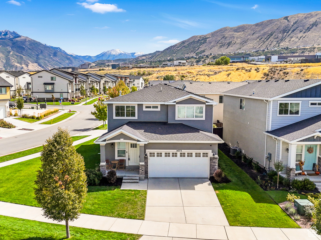 View of front of home with a front yard, a mountain view, and a garage