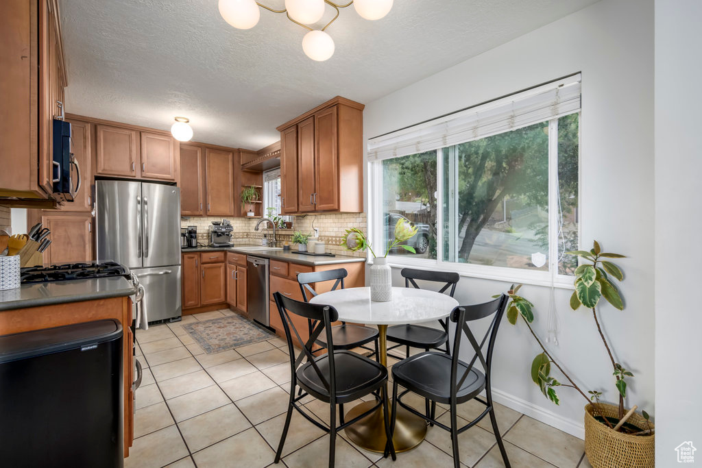 Kitchen with a textured ceiling, sink, stainless steel appliances, backsplash, and light tile patterned floors