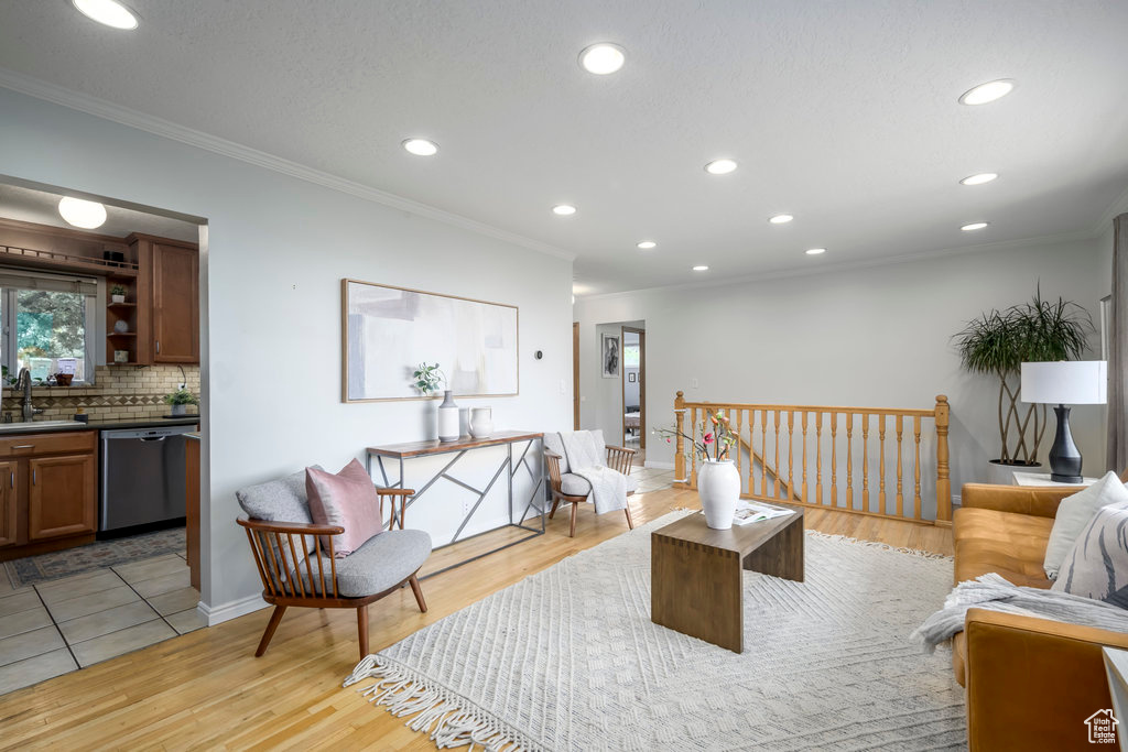 Living room with light wood-type flooring, sink, and crown molding