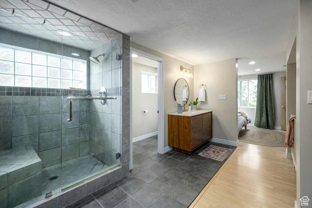 Bathroom featuring a shower with shower door, a healthy amount of sunlight, vanity, and hardwood / wood-style flooring