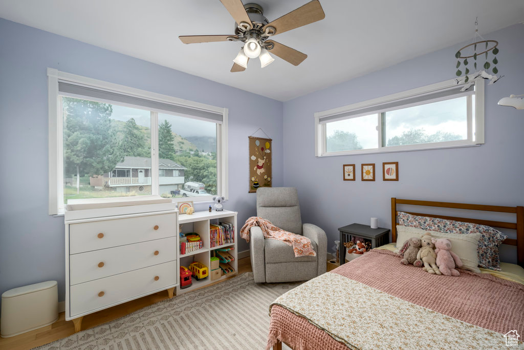 Bedroom with light hardwood / wood-style floors, multiple windows, and ceiling fan