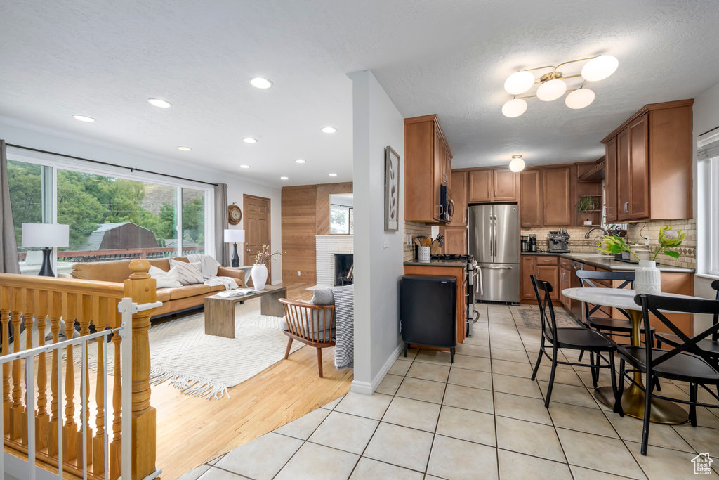 Kitchen featuring light hardwood / wood-style flooring, a textured ceiling, tasteful backsplash, and stainless steel fridge