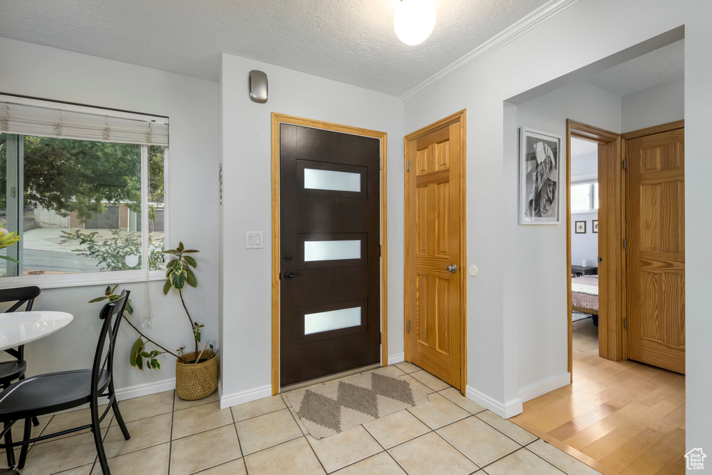 Entrance foyer featuring a textured ceiling, ornamental molding, and light hardwood / wood-style flooring