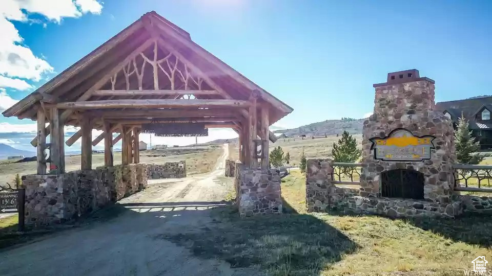 View of vehicle parking featuring an outdoor stone fireplace and a gazebo