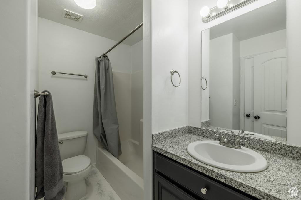 Full bathroom featuring shower / bath combination with curtain, vanity, toilet, and a textured ceiling