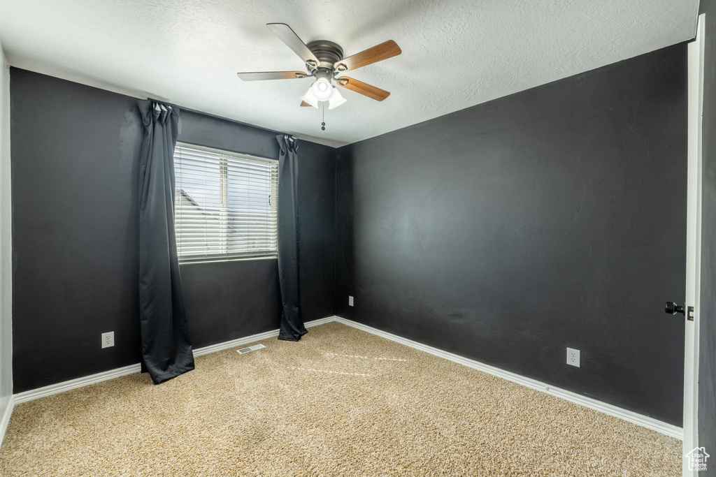 Carpeted spare room featuring a textured ceiling and ceiling fan