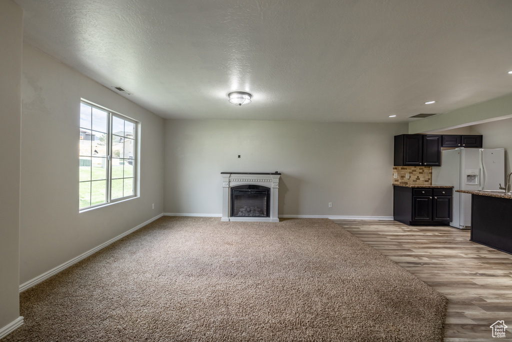 Unfurnished living room featuring a textured ceiling and light hardwood / wood-style floors