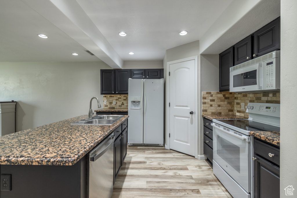 Kitchen featuring decorative backsplash, white appliances, a center island, light hardwood / wood-style flooring, and sink