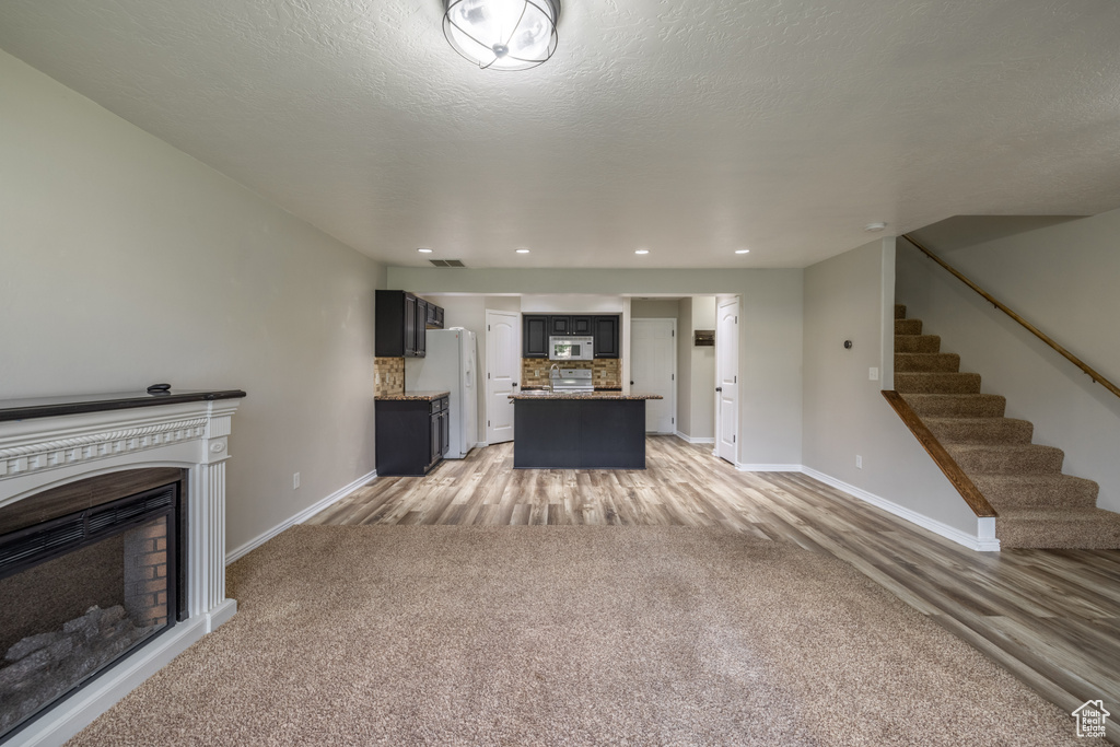 Unfurnished living room with light carpet and a textured ceiling