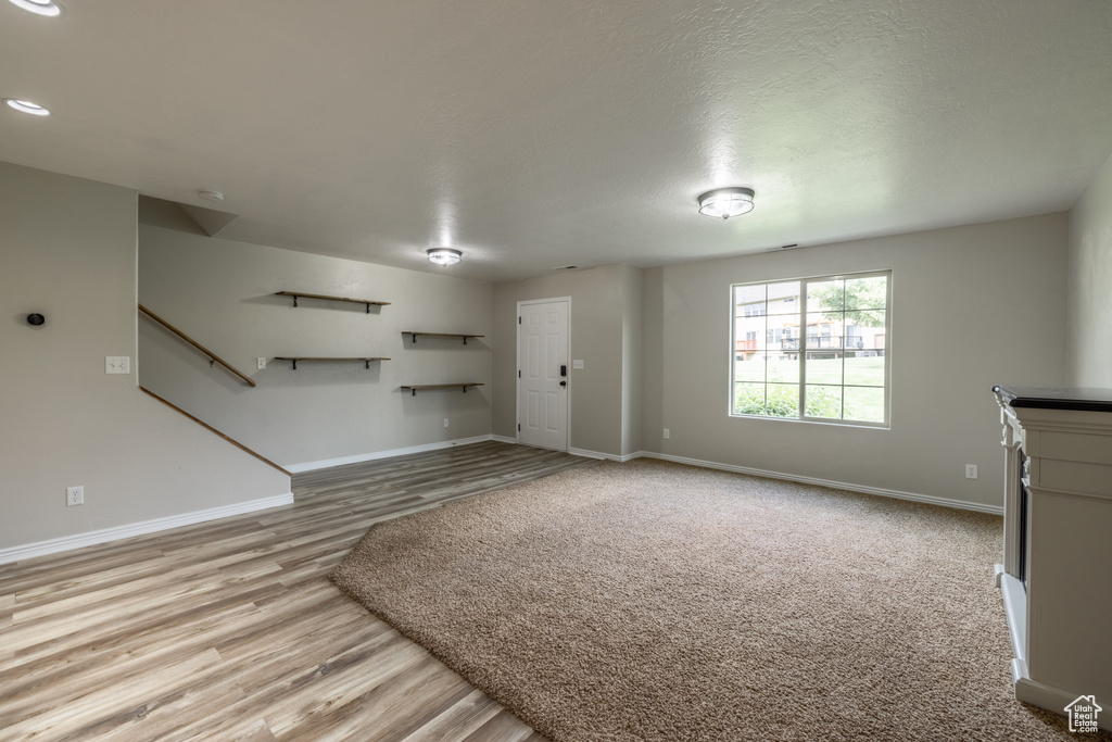 Unfurnished living room with light hardwood / wood-style flooring and a textured ceiling