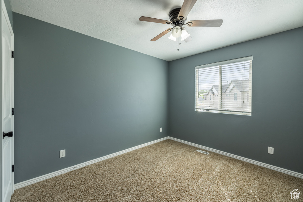 Spare room featuring carpet floors, a textured ceiling, and ceiling fan