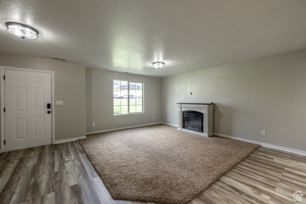 Unfurnished living room featuring a textured ceiling and hardwood / wood-style flooring