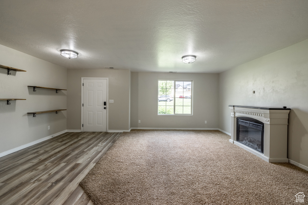 Unfurnished living room with a textured ceiling and hardwood / wood-style floors