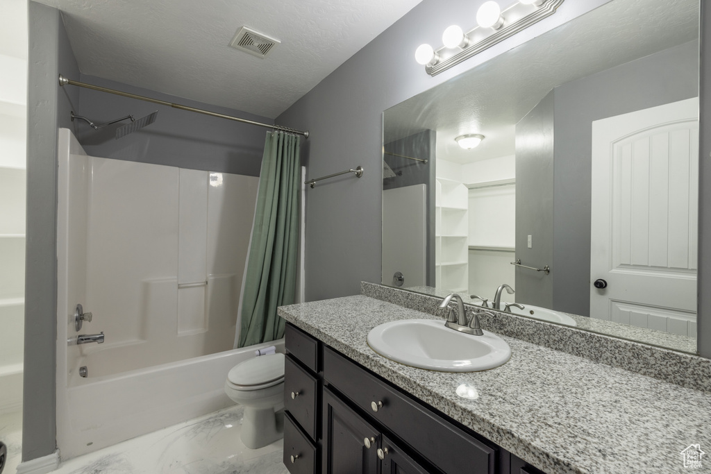 Full bathroom with vanity, shower / tub combo, toilet, and a textured ceiling