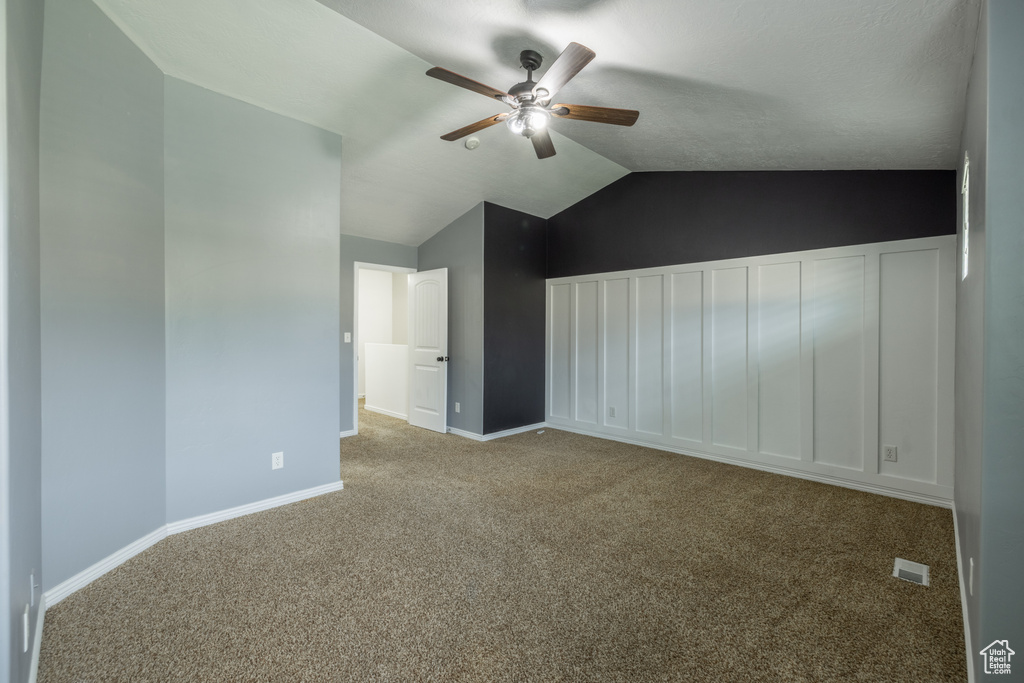 Empty room featuring ceiling fan, light colored carpet, and vaulted ceiling