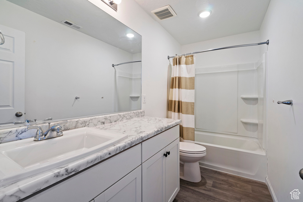 Full bathroom with wood-type flooring, vanity, toilet, and shower / bath combo with shower curtain