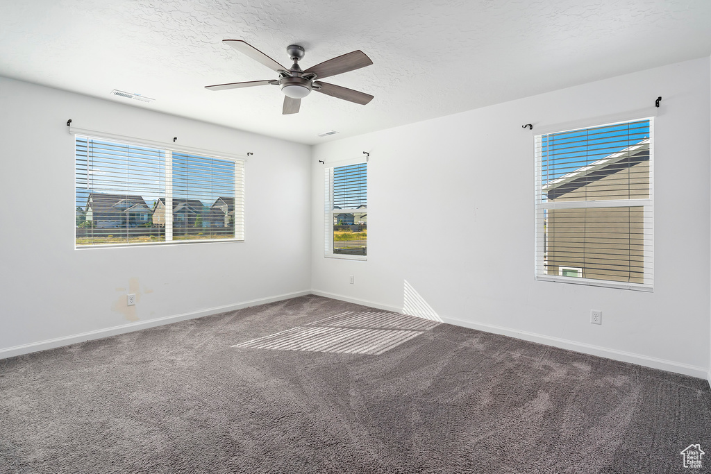 Spare room with carpet floors, a healthy amount of sunlight, and ceiling fan