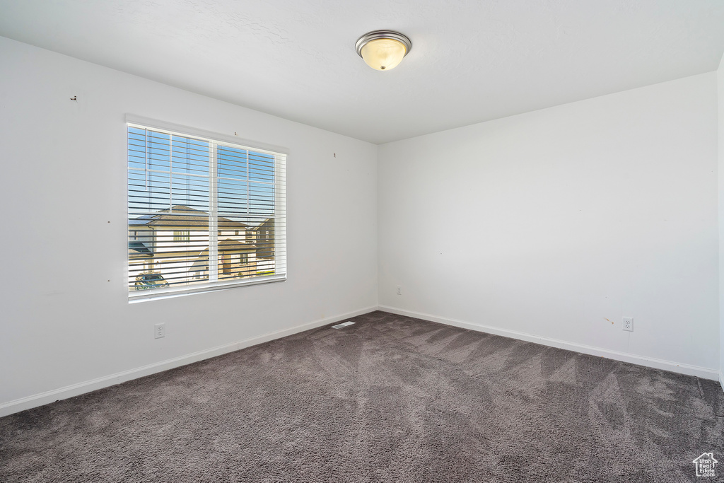 Empty room featuring dark colored carpet