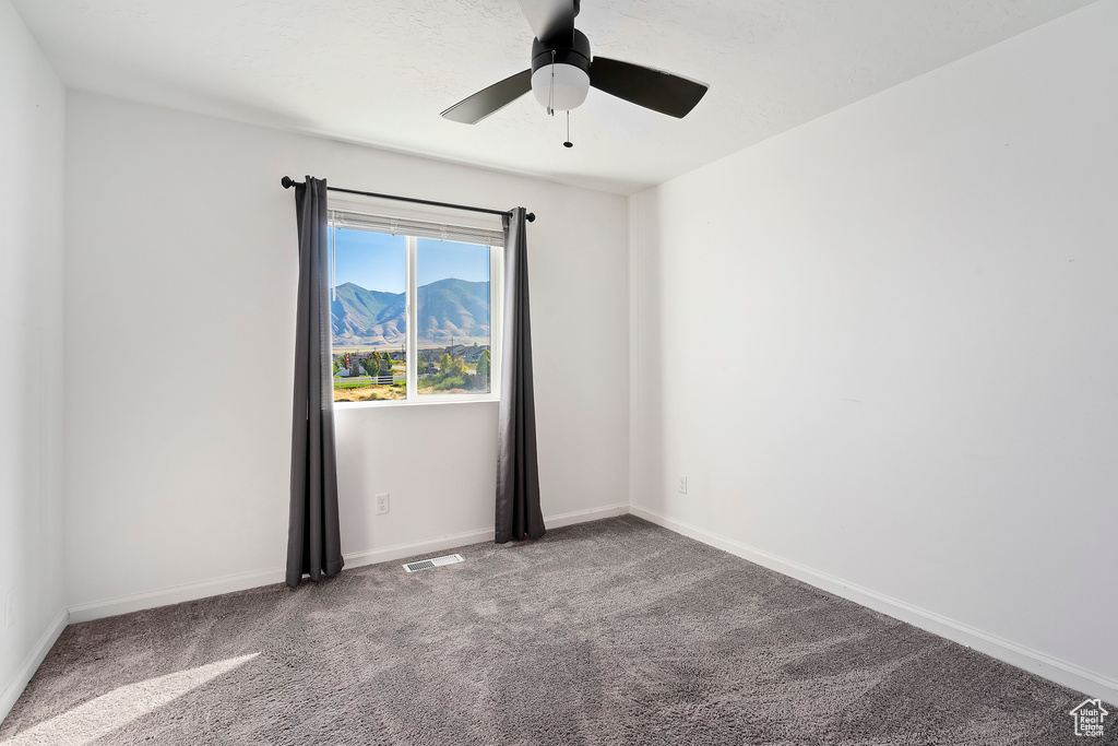 Carpeted spare room featuring ceiling fan and a mountain view