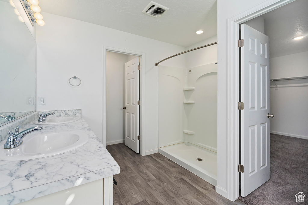 Bathroom featuring a shower, vanity, and hardwood / wood-style floors