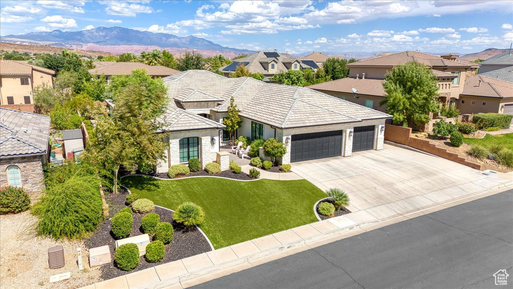 View of front of home with a garage, a front lawn, and a mountain view