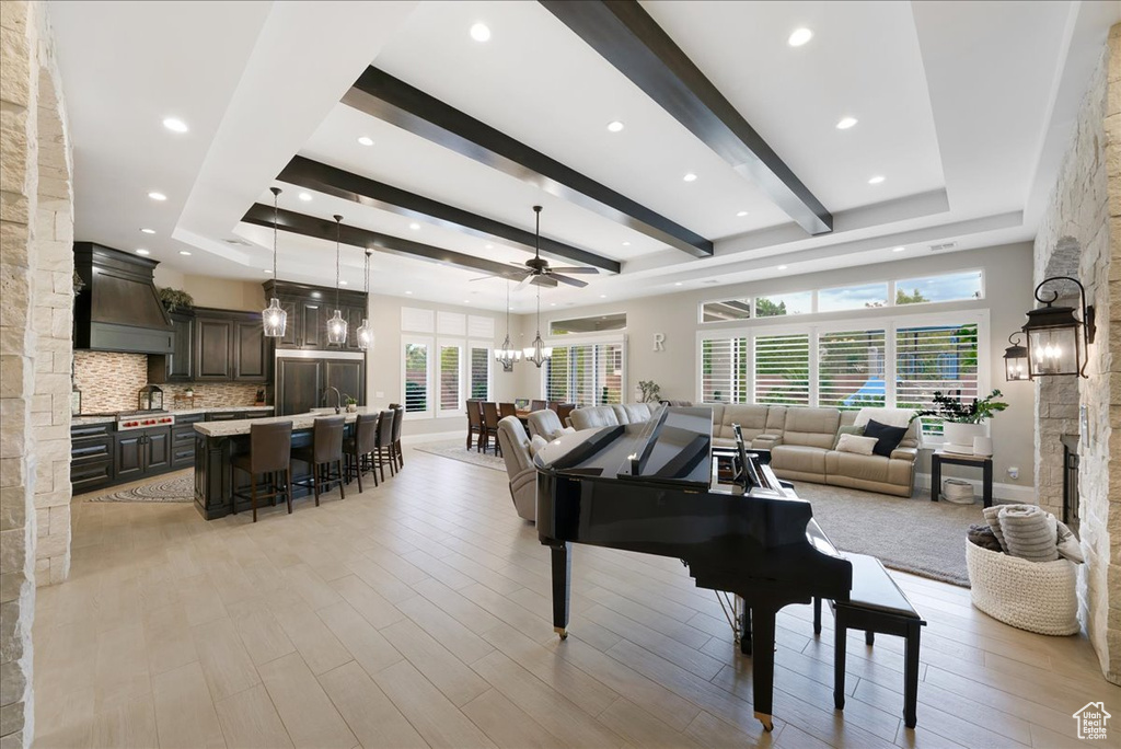 Interior space featuring light hardwood / wood-style flooring, a raised ceiling, ceiling fan with notable chandelier, and a fireplace