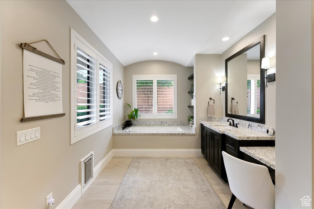 Bathroom with lofted ceiling, a tub, hardwood / wood-style floors, and vanity