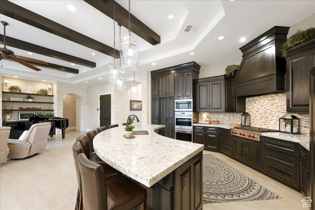 Kitchen with ceiling fan, sink, a large island, stainless steel appliances, and a kitchen bar