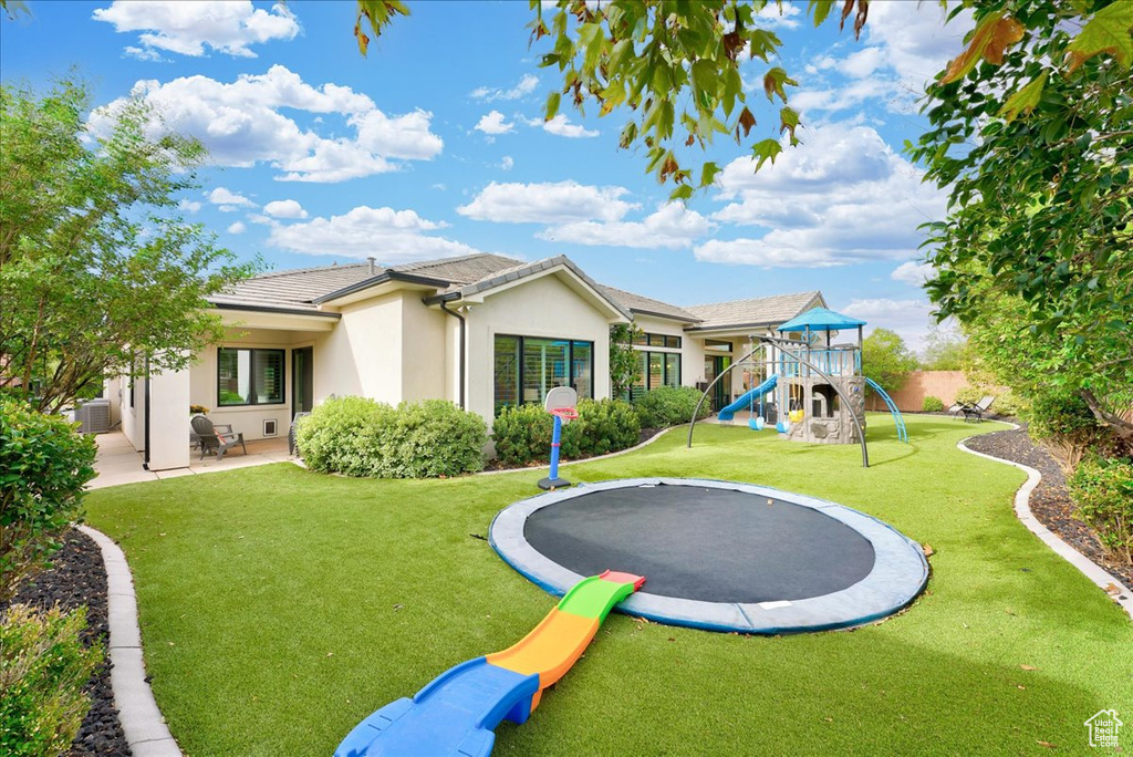 Exterior space with a playground, a yard, and a trampoline