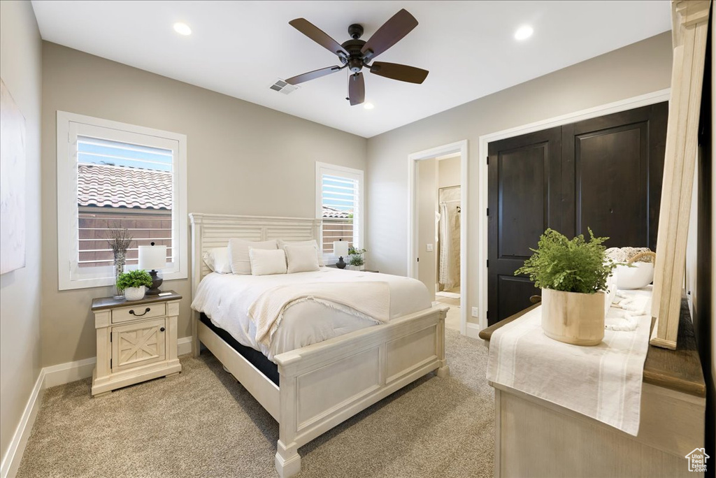 Carpeted bedroom with ceiling fan and ensuite bathroom