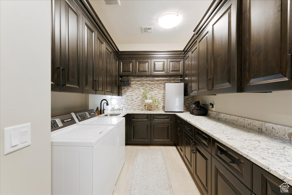 Washroom with cabinets, sink, and washing machine and dryer