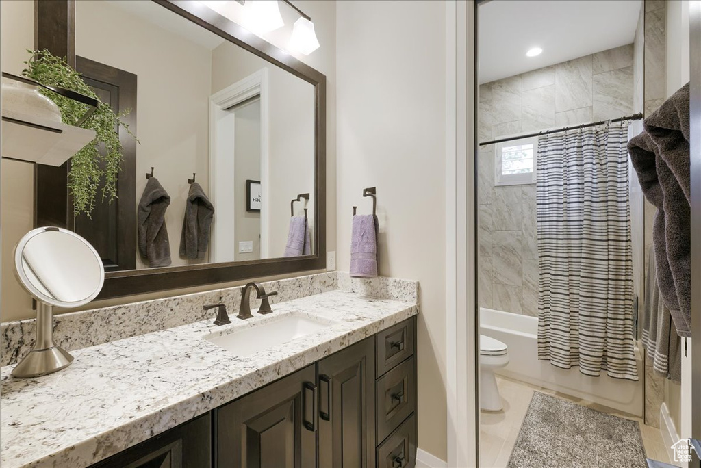 Full bathroom with shower / bath combo with shower curtain, tile patterned flooring, vanity, and toilet