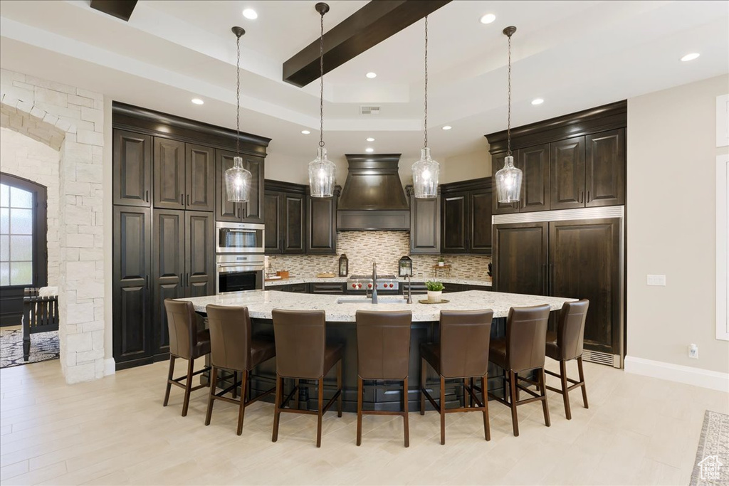 Kitchen featuring a kitchen breakfast bar, stainless steel appliances, backsplash, dark brown cabinetry, and a spacious island