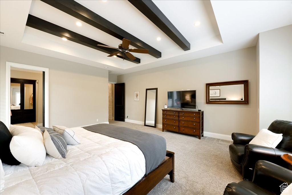 Carpeted bedroom with a raised ceiling, beamed ceiling, and ceiling fan