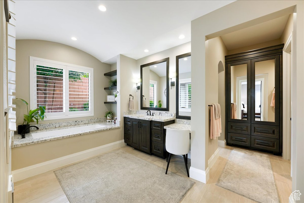 Bathroom with a tub to relax in, wood-type flooring, and vanity