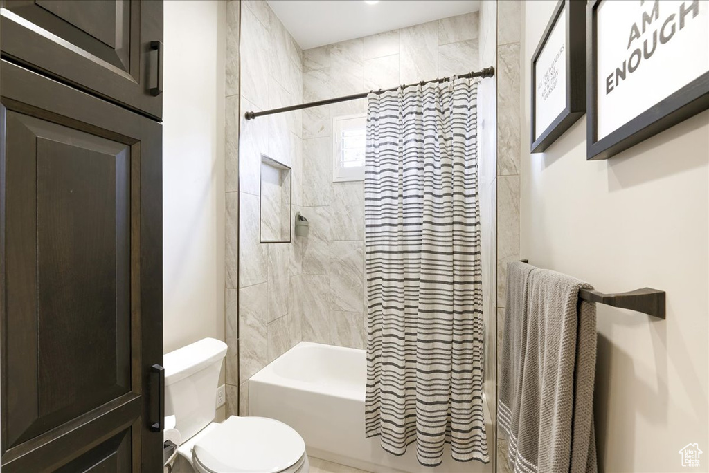 Bathroom featuring shower / bathtub combination with curtain and toilet