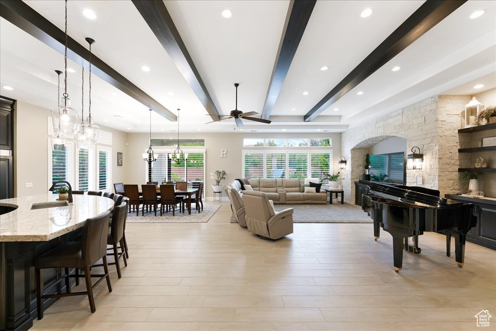 Living room featuring light wood-type flooring, beam ceiling, sink, and ceiling fan