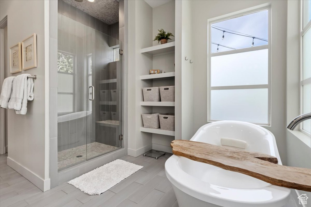 Bathroom with plus walk in shower, a wealth of natural light, built in shelves, and hardwood / wood-style floors