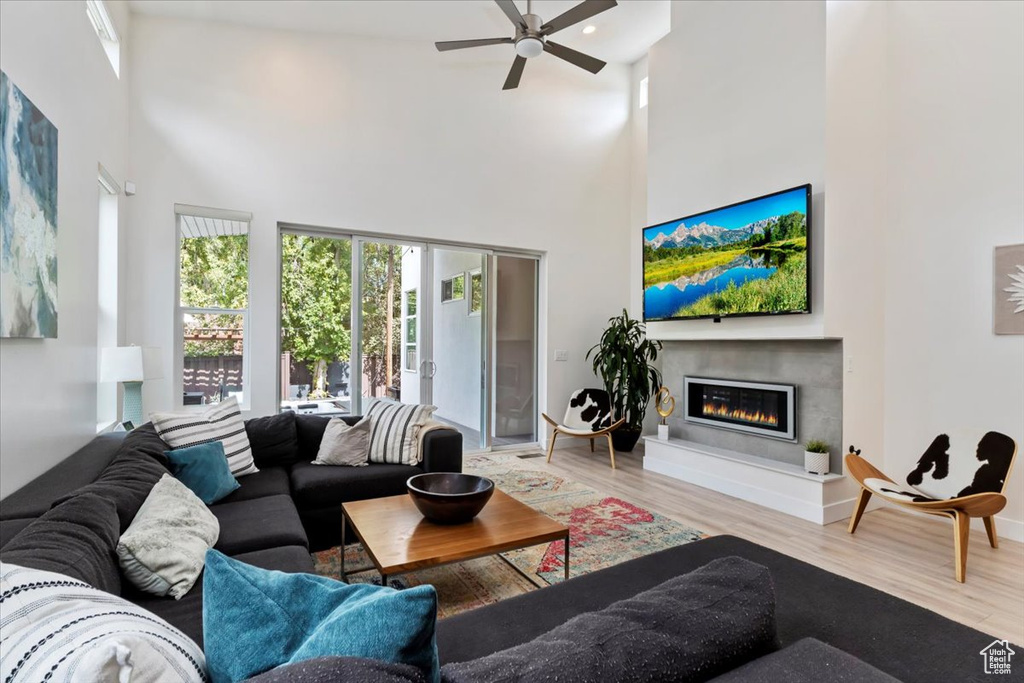 Living room with wood-type flooring, a towering ceiling, and ceiling fan