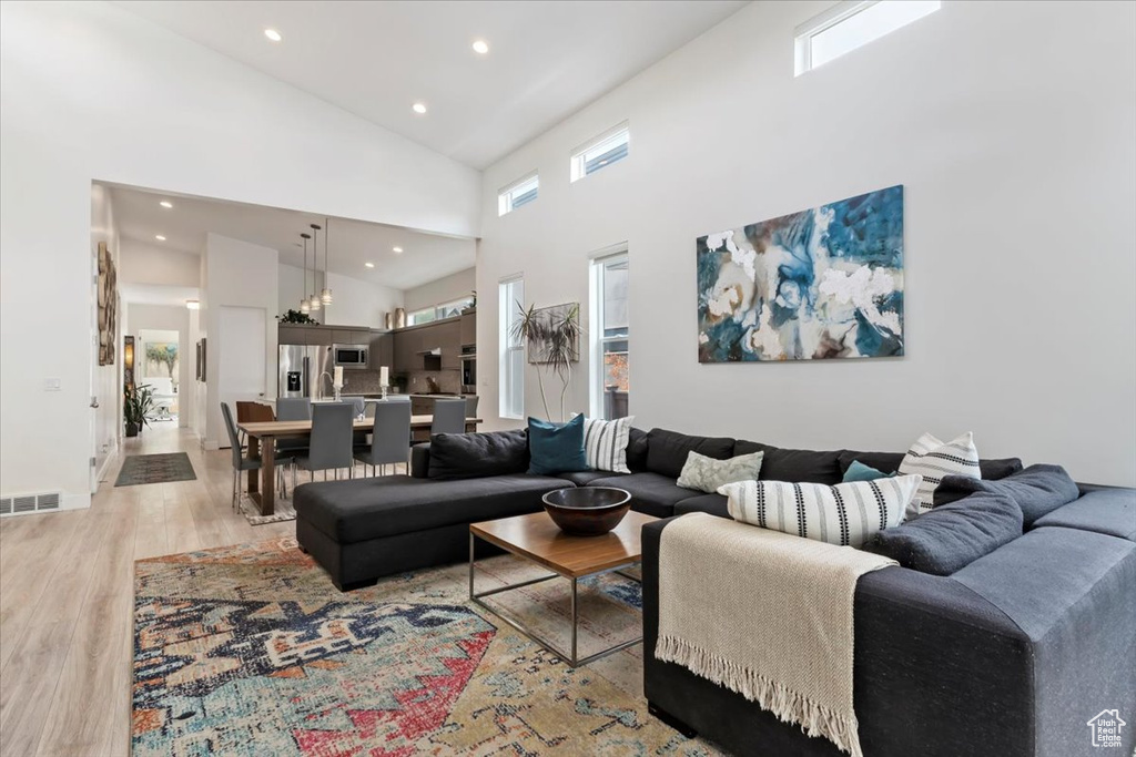 Living room with high vaulted ceiling and light hardwood / wood-style flooring