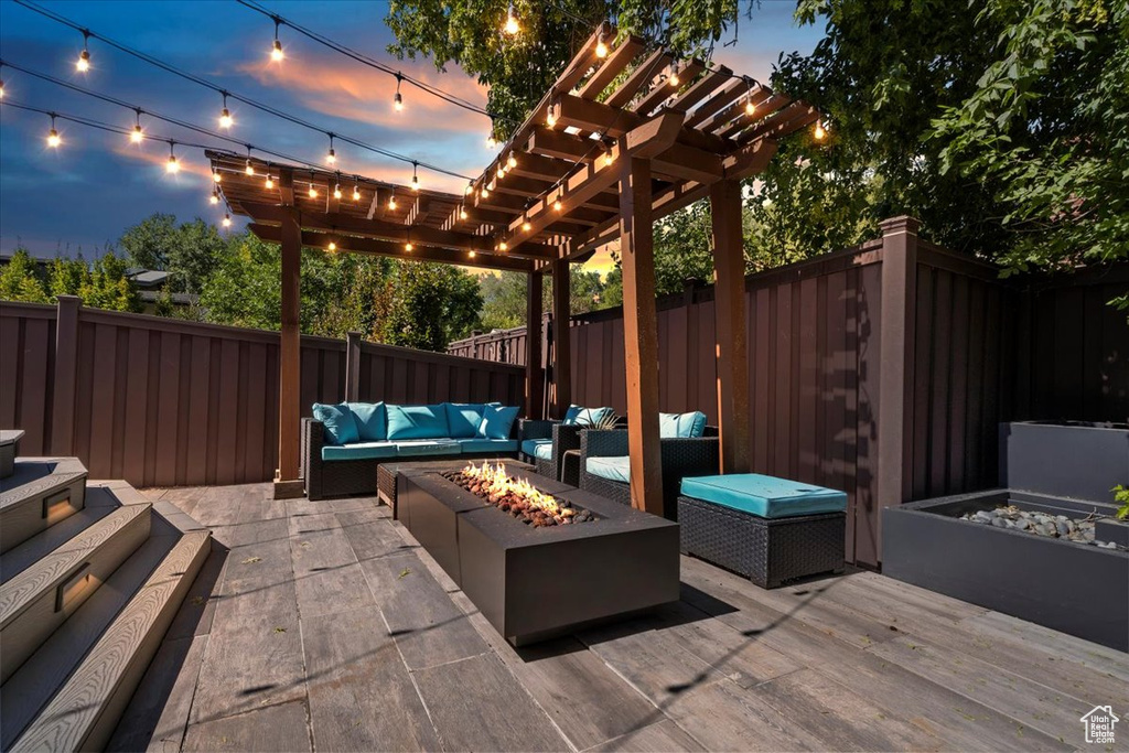 Patio terrace at dusk with an outdoor living space with a fire pit, a deck, and a pergola