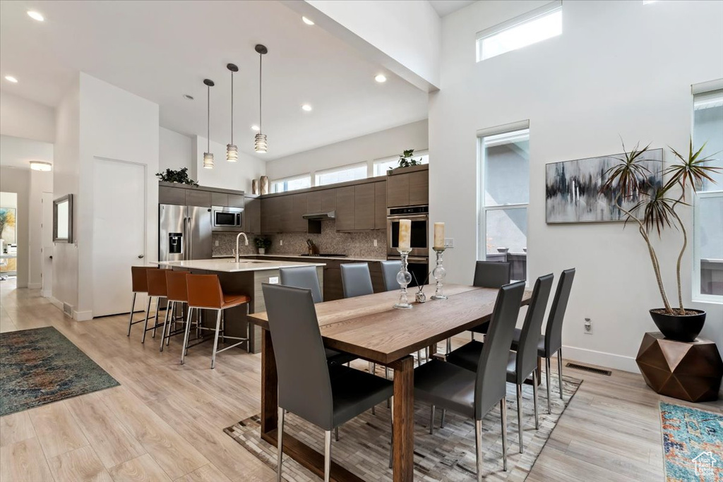 Dining room with light wood-type flooring, a high ceiling, and plenty of natural light