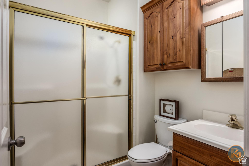 Bathroom featuring walk in shower, vanity, and toilet