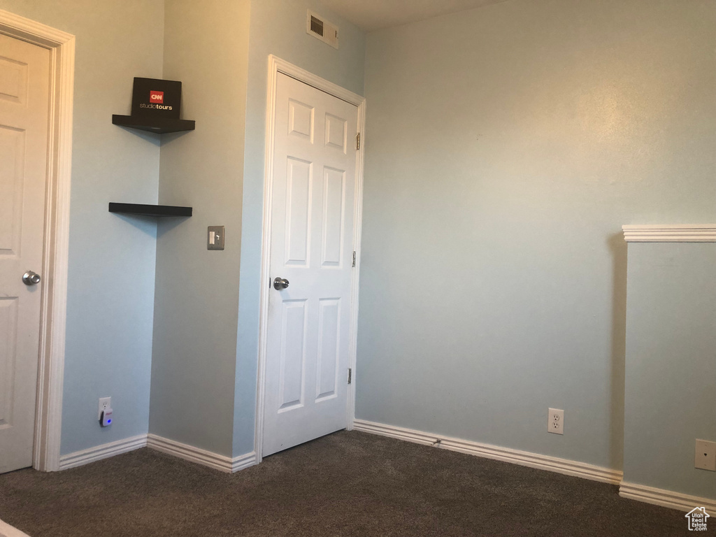 Unfurnished bedroom featuring dark colored carpet